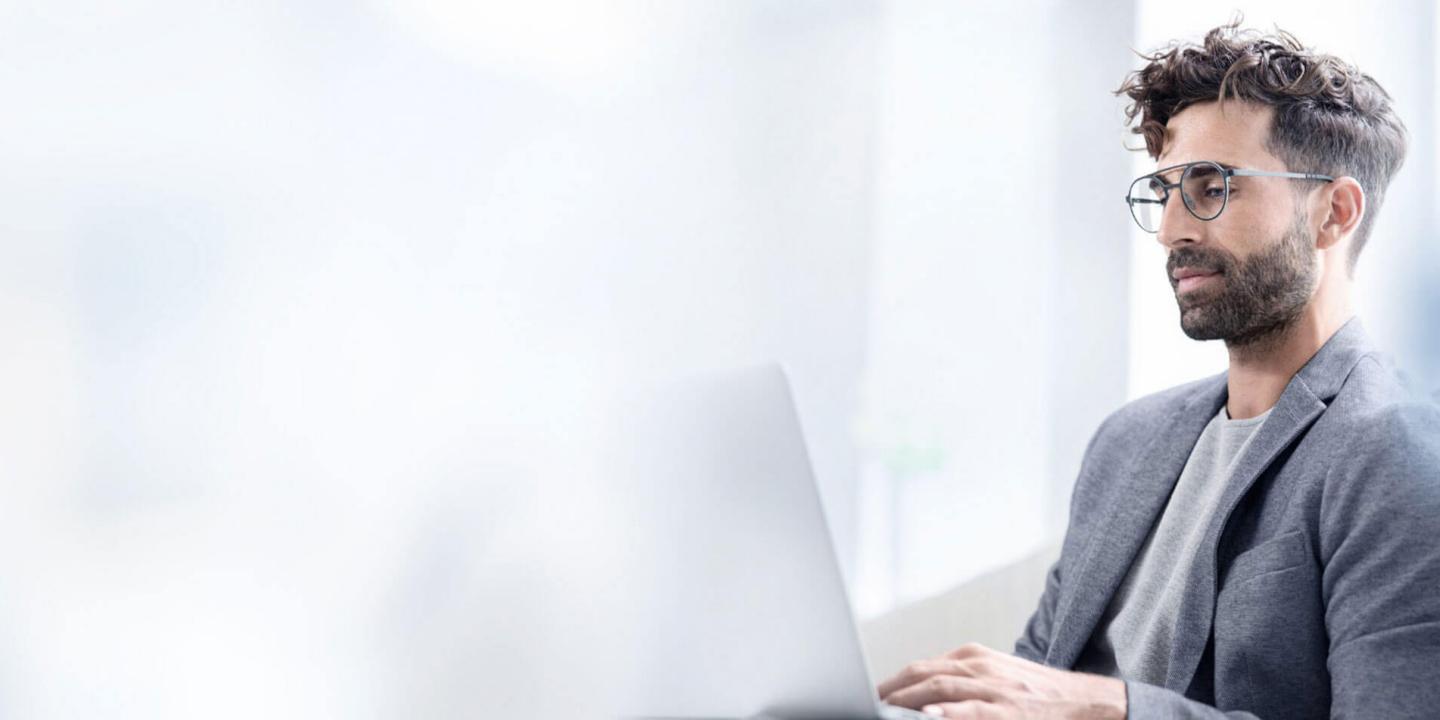 Remote tech professional working at a laptop wearing glasses